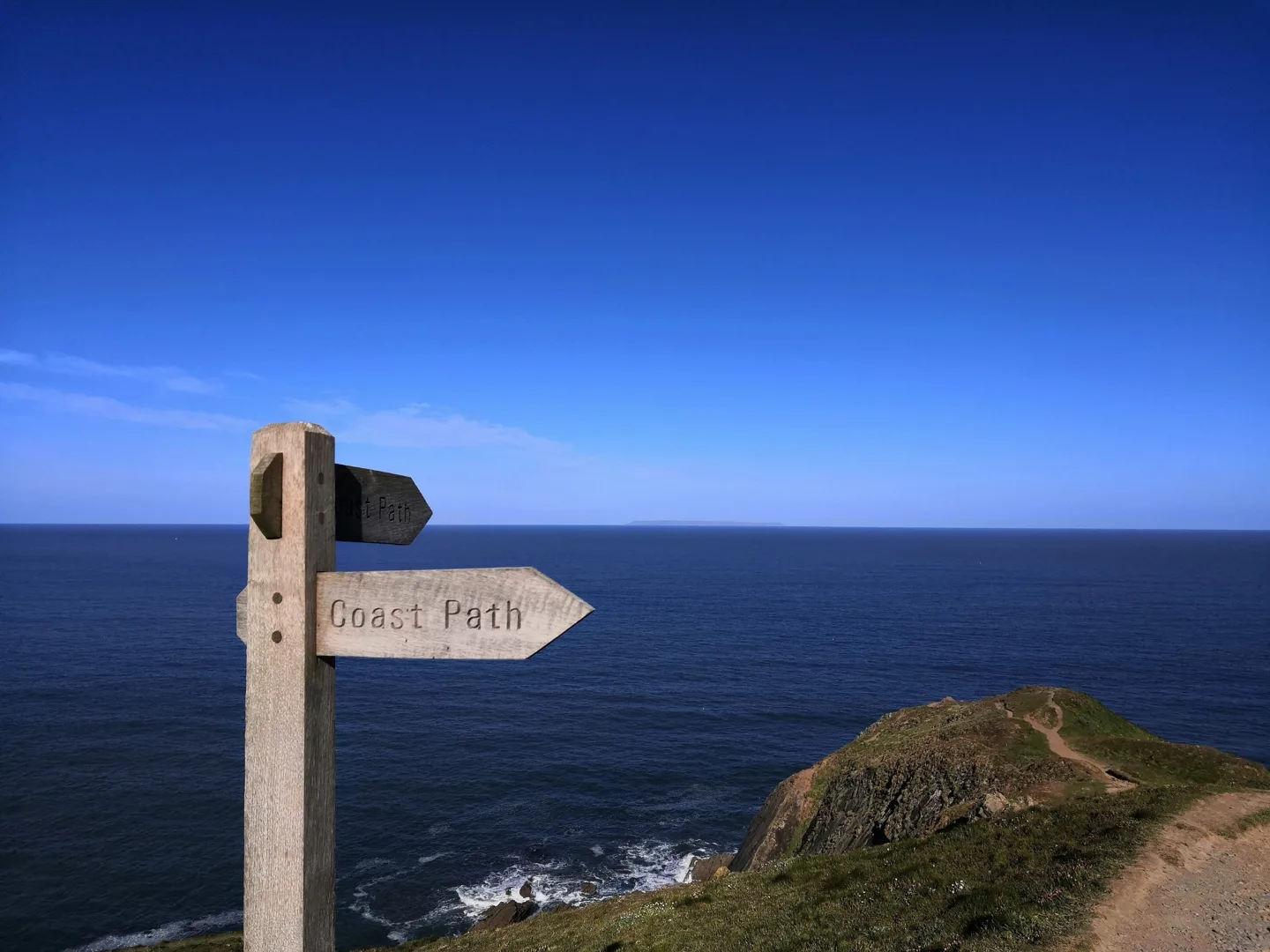 Coast Path signpost overlooking the sea at Baggy Point